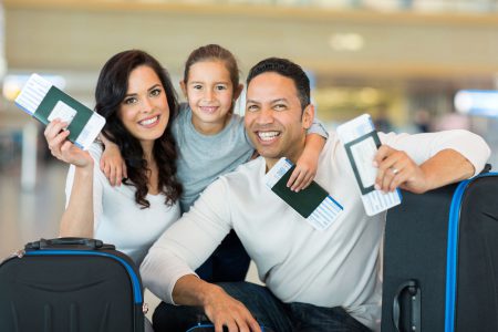 30771955 - happy family holding boarding pass and passport at airport